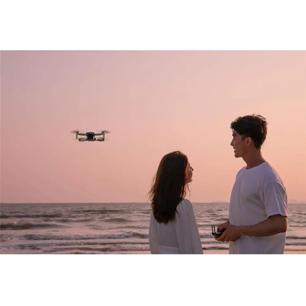 Couple flying DJI Mavic Mini Combo Ultra Light Drone on a sunny beach