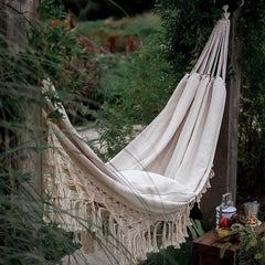 Cream-colored Boho Macrame Hammock with fringe for comfortable outdoor relaxation