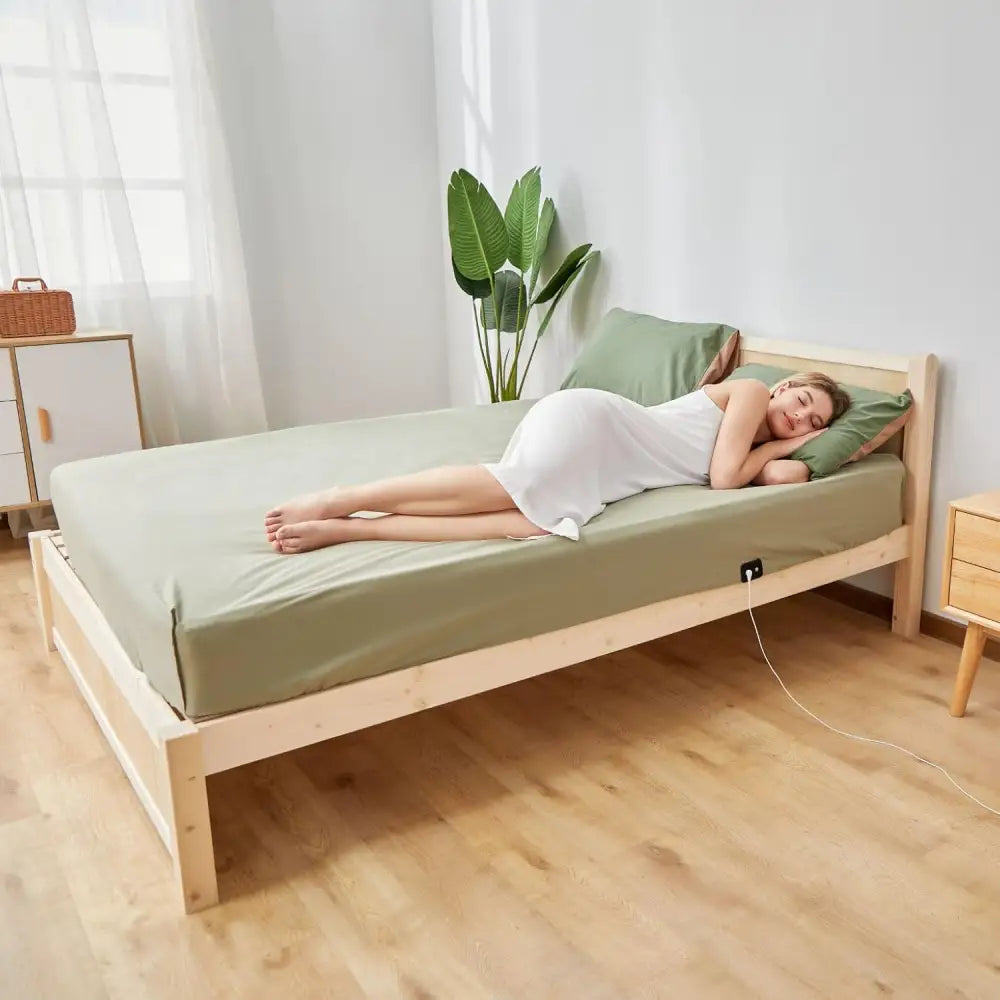 Wooden bed featuring green sheets and grounding earthing sheet for inflammation relief