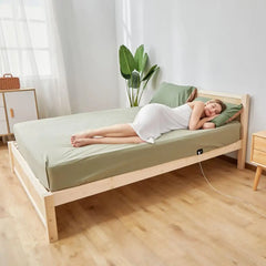 Wooden bed featuring green sheets and grounding earthing sheet for inflammation relief