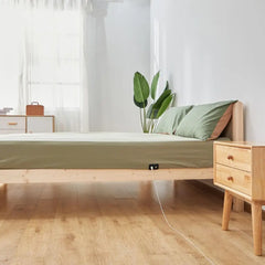 Wooden bed frame with green bedding and grounding earthing sheet for inflammation relief