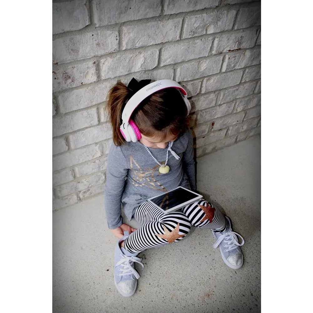 Girl using Pink WT-7S Light-Up Bluetooth Headset while enjoying a tablet